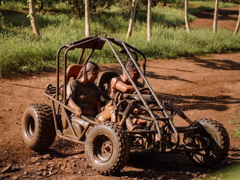 Riders in dirty buggy turning down muddy track
