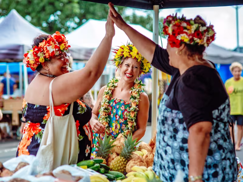 Women at a fruit stall market hi5 and smile