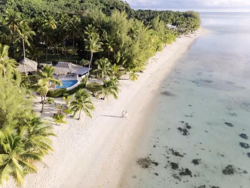 Aerial view of a couple walking on the beach by a lagoon