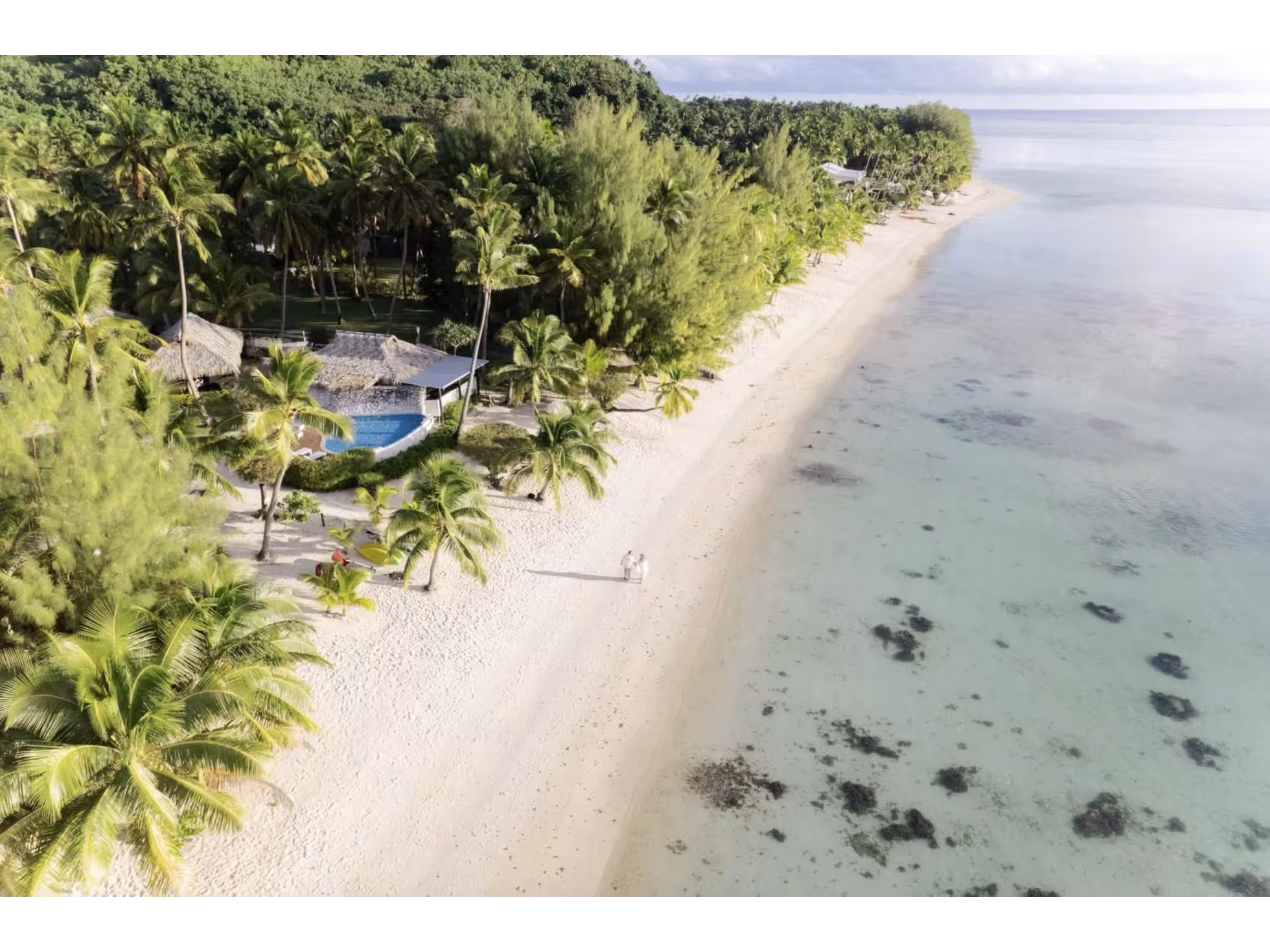 Aerial view of a couple walking on the beach by a lagoon